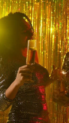 Vertical-Video-Of-Two-Women-In-Nightclub-Or-Bar-Dancing-Drinking-Alcohol-With-Sparkling-Lights-In-Background-1